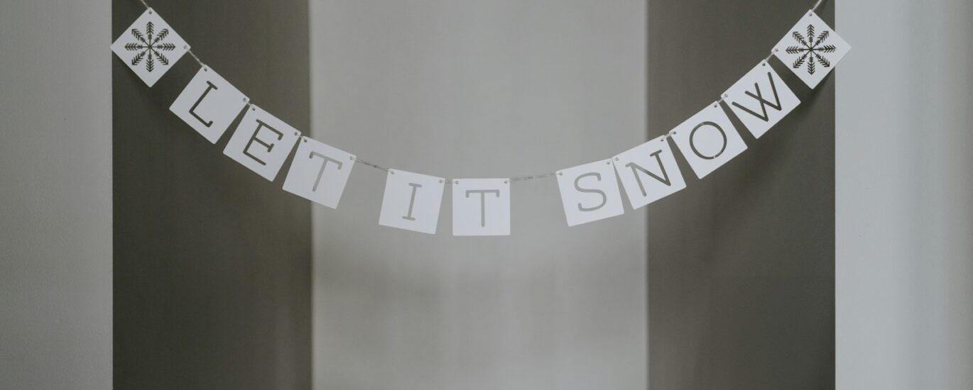 A sign that says let it snow hanging from a wall