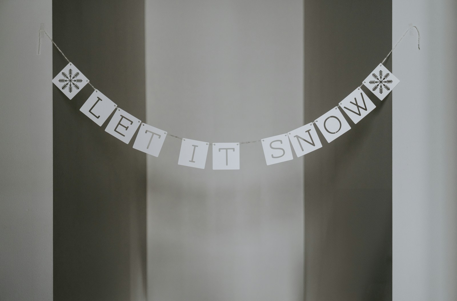 A sign that says let it snow hanging from a wall